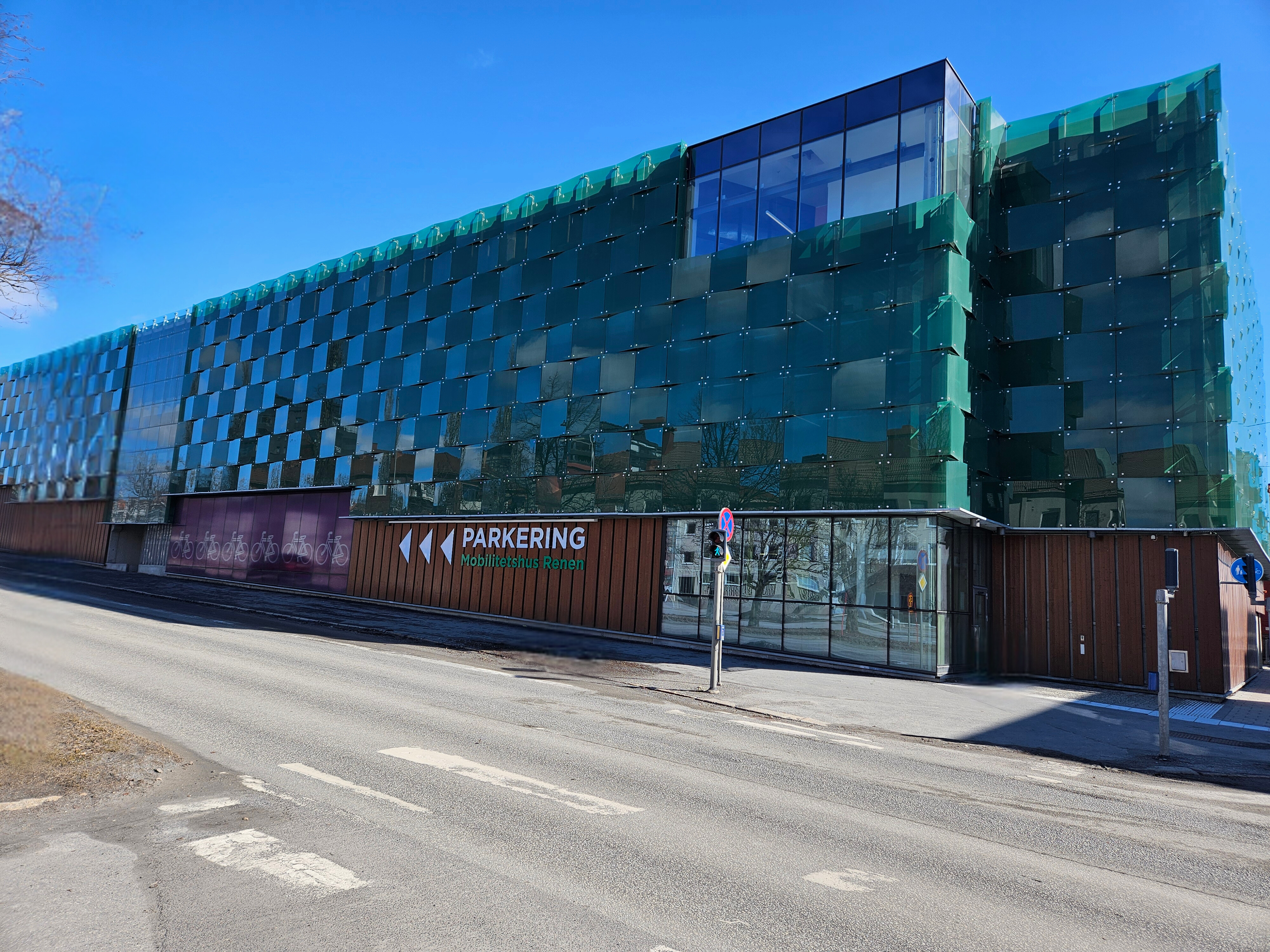 Grönt parkeringshus vid gata med trafikljus