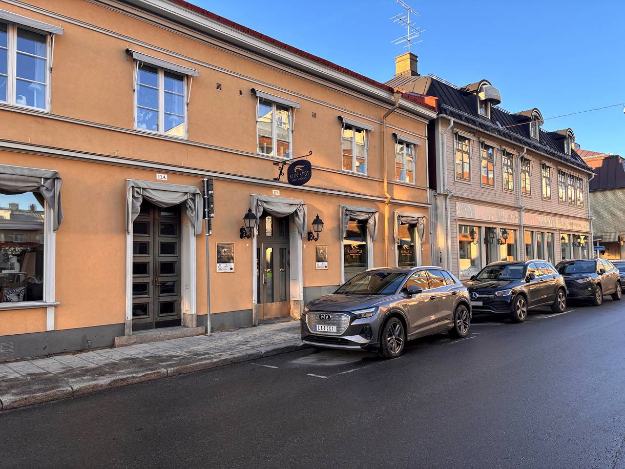 Butikslokal längs gata med parkerade bilar.